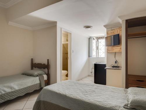 a hotel room with two beds and a bathroom at Hotel Estrela Do Vale in Ipatinga