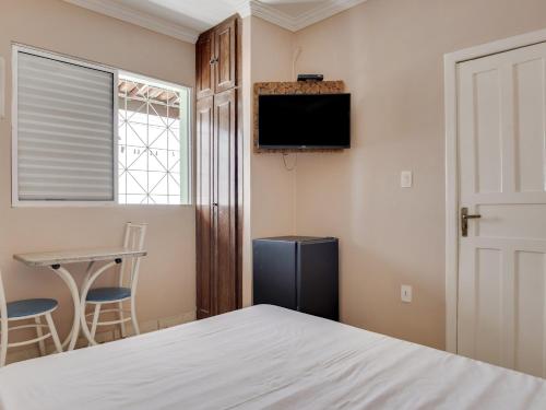 a bedroom with a bed and a tv and a table at Hotel Estrela Do Vale in Ipatinga