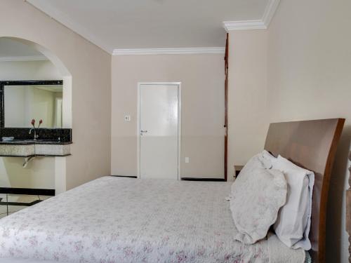 a white bedroom with a bed and a mirror at Hotel Estrela Do Vale in Ipatinga