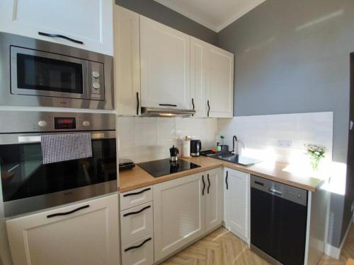 a kitchen with white cabinets and stainless steel appliances at Apartament Dworcowa 100 m do PKP in Kołobrzeg