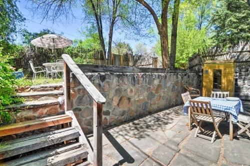 a patio with a table and chairs and a stone wall at Charming Santa Fe Studio Cabin with Patio and Yard! in Santa Fe