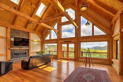 a large living room with a fireplace and large windows at Naples Cabin with Lake Views and Wraparound Deck! in Naples