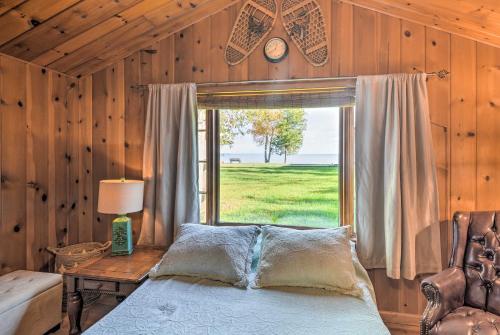 a bedroom with a bed and a large window at Lovely Lake Huron Getaway Beach Access and Kayaks! in Evergreen Shores