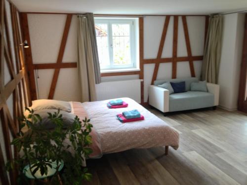 a room with a bed and a couch and a window at Au numéro 6 in Obersteinbach