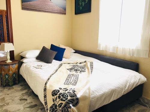 1 dormitorio con 1 cama con sábanas blancas y almohadas azules en El Rico Rincón de Sanlúcar la Mayor, en Sanlúcar la Mayor