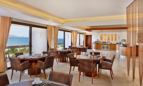 a dining room with tables and chairs and the ocean at InterContinental Aqaba by IHG in Aqaba