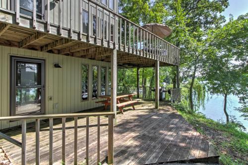 a house with a deck next to the water at Waupaca Lakefront Home with Pool Table and Dock! in Waupaca