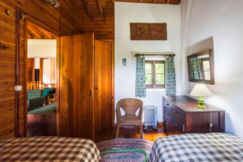 a bedroom with two beds and a desk and a chair at Casa da Cascata in Furnas