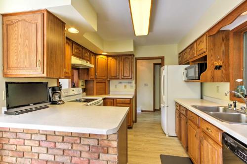 a kitchen with wooden cabinets and a white refrigerator at Waupaca Lakefront Home with Pool Table and Dock! in Waupaca