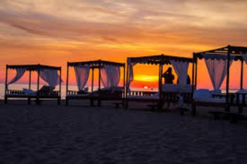 eine Gruppe Picknicktische am Strand bei Sonnenuntergang in der Unterkunft La Suite sul Borgo in Fregene