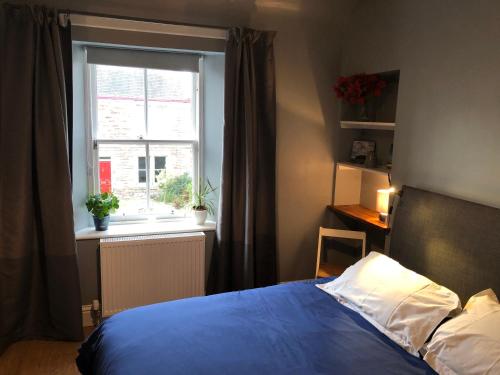um quarto com uma cama azul e uma janela em Hopetoun Haven em Gullane
