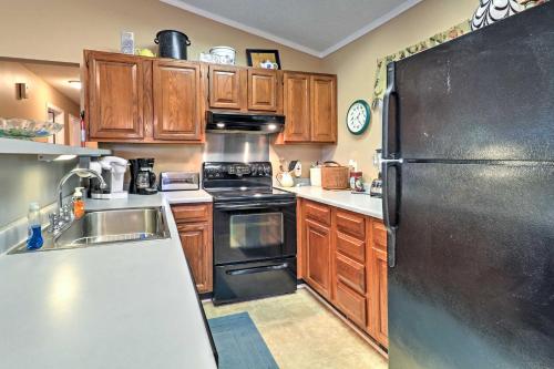 a kitchen with wooden cabinets and a black refrigerator at Lakefront Cottage with Private Hot Tub! in Buckhead