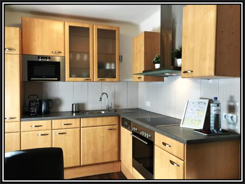 una cucina con armadi in legno e piano di lavoro nero di Sankt Veit Apartment a Sankt Veit an der Glan