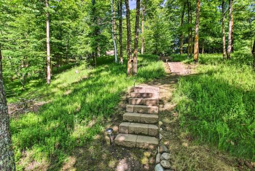 a stone path in a forest with trees at Trout Lake Cabin with Private Dock, Kayaks and Loft! in Grand Rapids