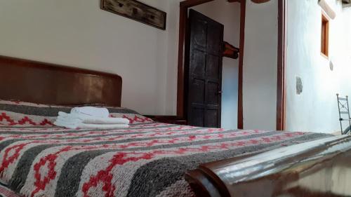 1 dormitorio con 1 cama con manta roja y blanca en Hostal Tierra Andina Cafayate en Cafayate