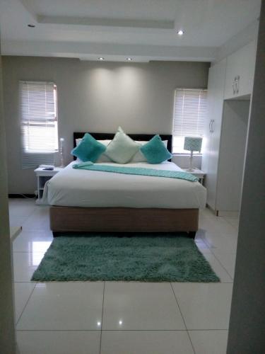 een slaapkamer met een groot bed met blauwe kussens bij Shoes guest house 2 in Mthatha