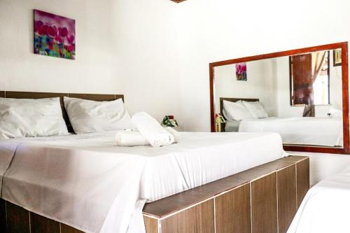 um quarto com 2 camas e um espelho grande em Cururupe Praia Hotel em Ilhéus
