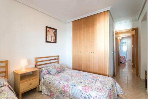 アリカンテにあるSpacious Beachside Apartment with Beautiful Sea Viewsのベッドルーム1室(ベッド1台付)、木製キャビネットが備わります。