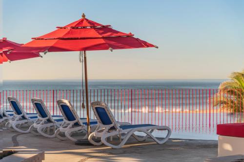 a row of chairs and an umbrella on a beach at Grand Decameron Los Cabos, A Trademark All-Inclusive Resort in San José del Cabo