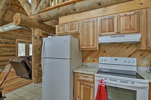 a kitchen with a white refrigerator and wooden cabinets at Custom Log Cabin with Deck and 45 Acres By Pine River! in Tustin