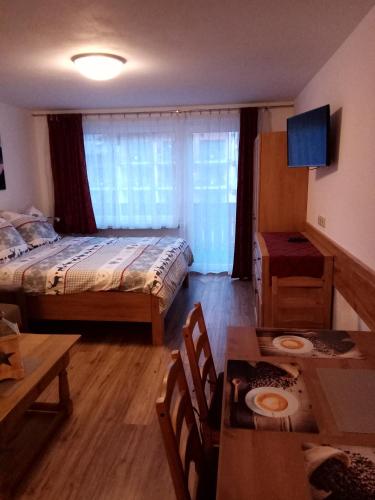 a bedroom with a bed and a table and a dining room at Apartmán Josef in Kaprun