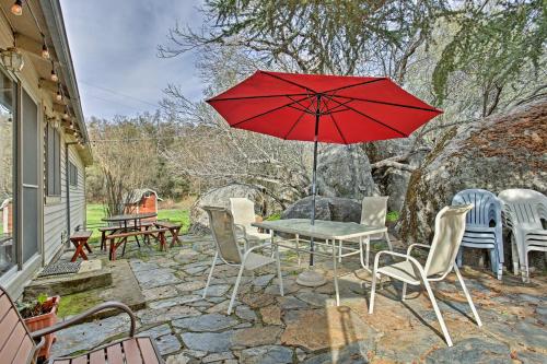 a patio with a table and chairs and a red umbrella at Cozy Home with Patio Near Yosemite National Park! in Mariposa