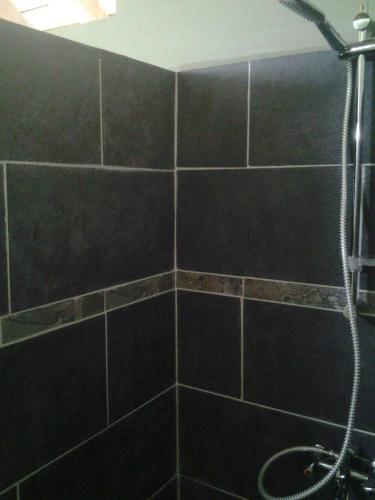 W wyłożonej czarnymi kafelkami łazience znajduje się prysznic. w obiekcie Fare Manutea w Nuku Hiva