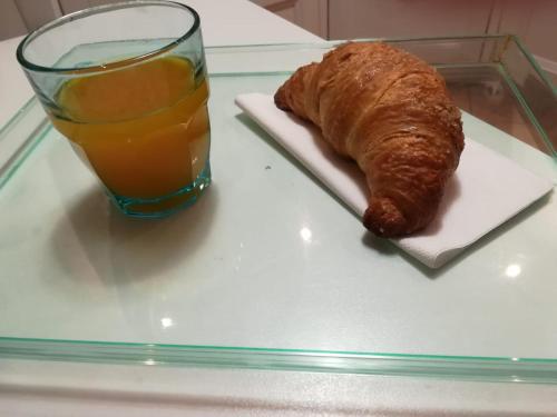 a glass plate with a glass of orange juice and a croissant at Il Nido B&B in Villa Dalegno