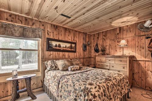 a bedroom with wooden walls and a bed and a window at Baldwin Cabin with Private Beach on Little Lake! in Baldwin
