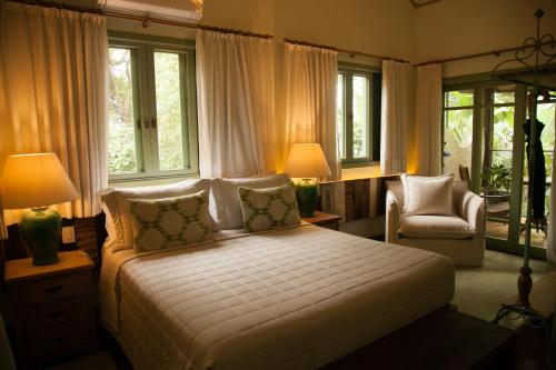 um quarto com uma cama, uma cadeira e janelas em Templo Do Ser em Ilhabela