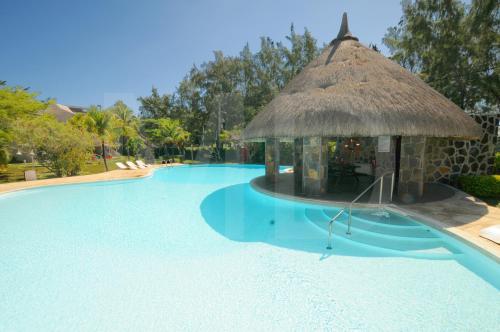 a large swimming pool with a thatch roof at Kenville in Pereybere