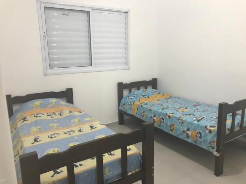 2 camas individuales en una habitación con ventana en Apartamento Praia de Boraceia - Litoral Norte SP en Boracéia