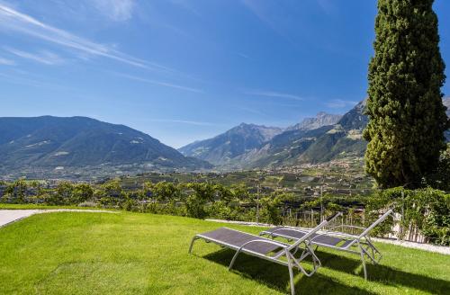 a bench sitting on top of a field with mountains at Beim Dorner in Schenna