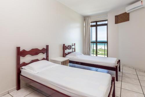 two beds in a room with a window at Apart Hotel Porto Príncipe in Cabo Frio
