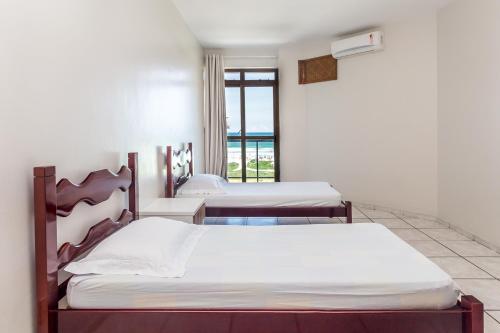 two beds in a room with a window at Apart Hotel Porto Príncipe in Cabo Frio