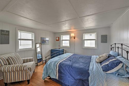 a bedroom with a bed and a chair and windows at Peaceful Cottage with Grill - Steps to Matunuck Beach in South Kingstown