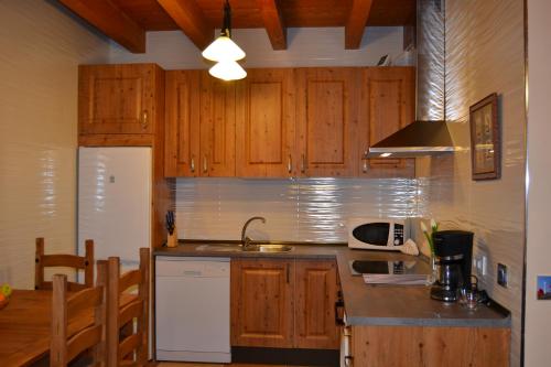 a kitchen with wooden cabinets and a white refrigerator at Casa rural La Senderilla in Avila