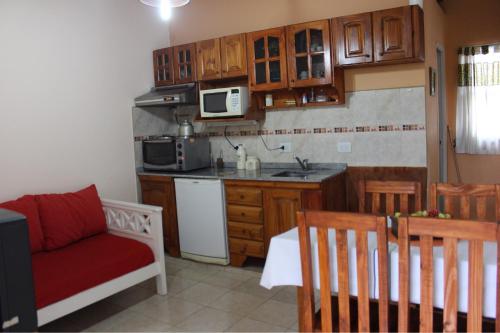 una cocina con armarios de madera y una silla roja. en Estación Aeropuerto Ezeiza en Lomas de Zamora