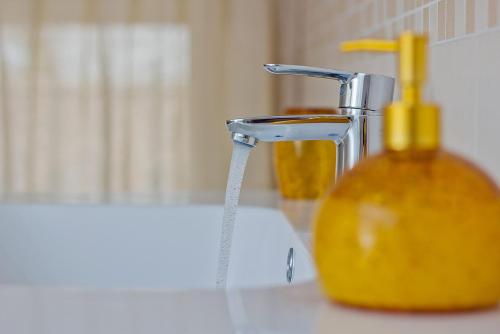 a sink with a faucet and a yellow soap container at Il Sogno in Avio