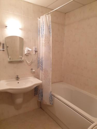 een badkamer met een wastafel, een bad en een douchegordijn bij Private Studio in Aspen Golf and Ski Resort in Razlog