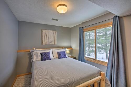 Un dormitorio con una cama con almohadas moradas y una ventana en Cozy Waterfront Fife Lake Cottage with Dock and Kayaks! en Fife Lake