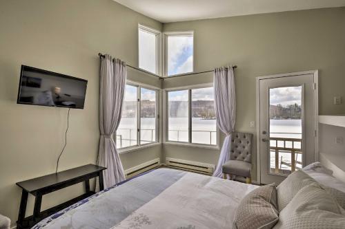 a bedroom with a bed and a tv and windows at Waterfront DeRuyter Home with Private Dock! in New Woodstock