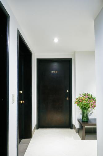 a black door in a hallway with a vase of flowers at Hotel Retiro 84 by MIJ in Bogotá