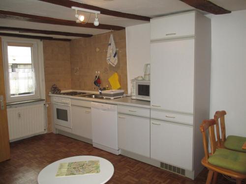 a kitchen with white cabinets and a sink and a table at Alsfelder Apartment in Alsfeld