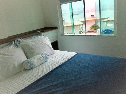 a bed with two pillows and a window in a bedroom at APARTAMENTO FRENTE MAR com vista fantástica in Balneário Camboriú
