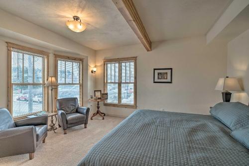 a bedroom with a bed and a chair and windows at Updated Townhome with Hot Tub - Walk to Downtown! in Red Lodge