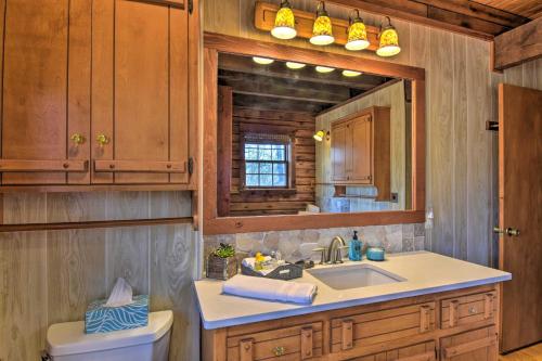 a bathroom with a sink and a toilet and a mirror at Luxury Log Cabin with 5 Private Acres and Hot Tub! in Pearcy