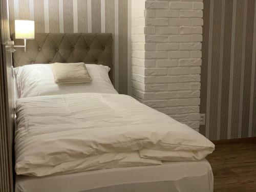 a large white bed in a room with a brick wall at Pension Vzhuru nohama in Jáchymov