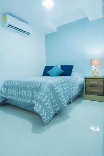 a blue bedroom with a bed and a night stand at Malecon Premium Rooms & Hotel in Santo Domingo