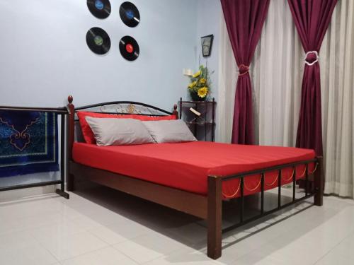 Homestay Seri Nipah Perlis في كانجار: غرفة نوم بسرير وبطانية حمراء